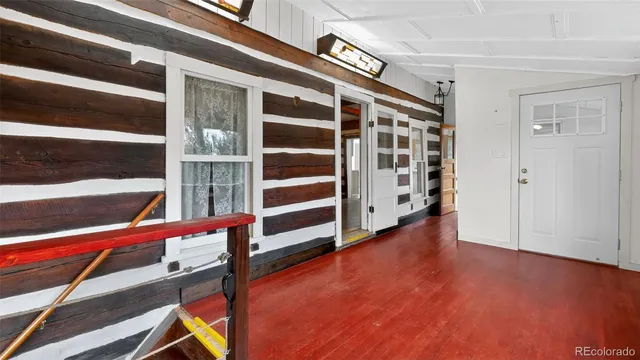 a view of an empty room with wooden floor and windows