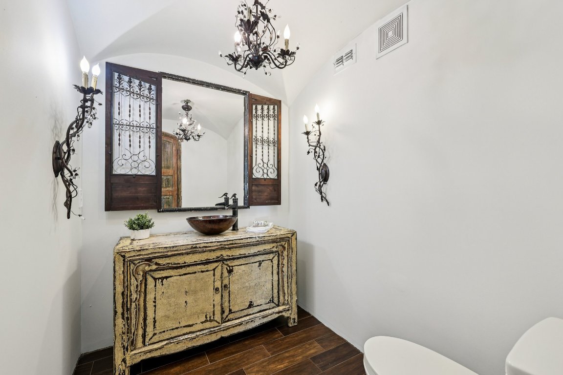 2706 Pearce Road Austin, TX 78730 - Photo 15 of 38 Old-world charm shines in this guest bath, featuring an antique-style distressed wood vanity and decorative iron sconces.