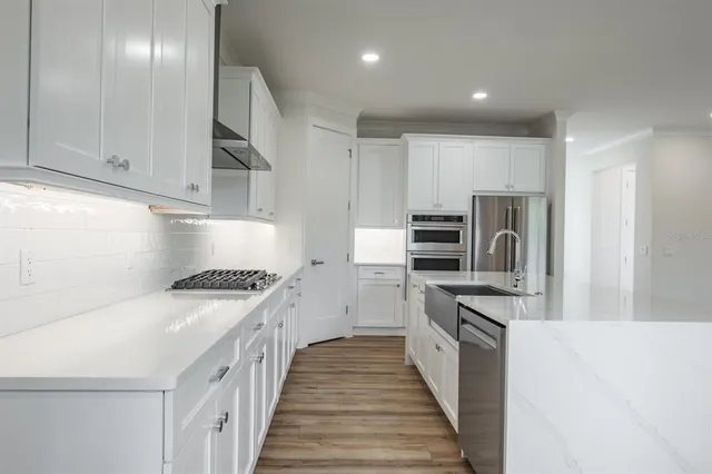 a kitchen with stainless steel appliances white cabinets and a refrigerator
