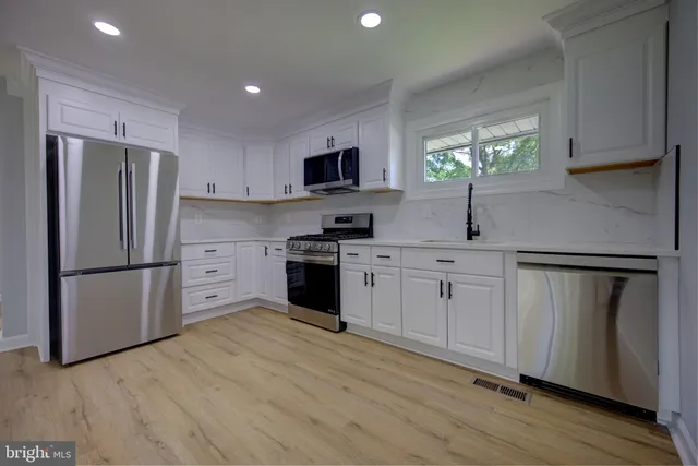 a kitchen with white cabinets stainless steel appliances and a window