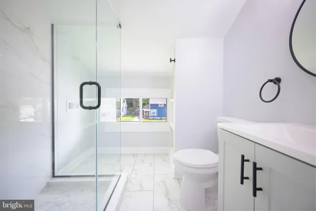 a bathroom with a granite countertop sink a toilet and a shower