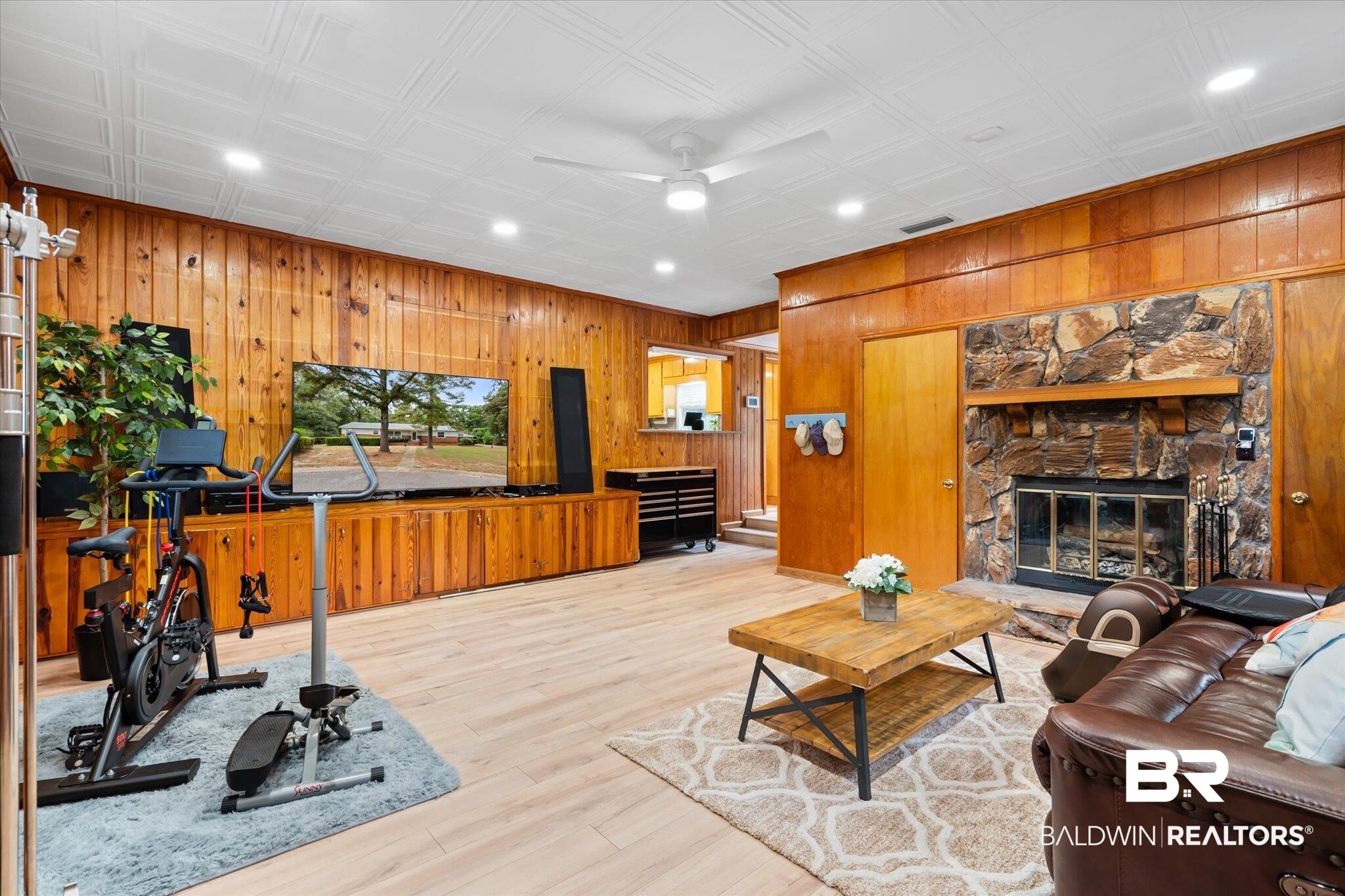 162 Bit And Spur Terrace Mobile, AL 36608 - Photo 10 of 29 Living room with a fireplace, wood walls, light wood-type flooring, and ceiling fan