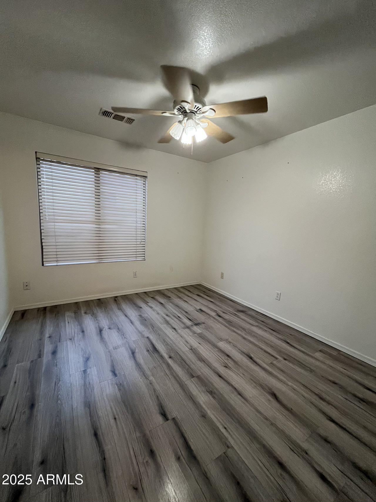1128 East Sheffield Avenue Gilbert, AZ 85296 - Photo 13 of 24 an empty room with wooden floor chandelier fan and windows