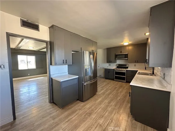a kitchen with a sink wooden floor and stainless steel appliances