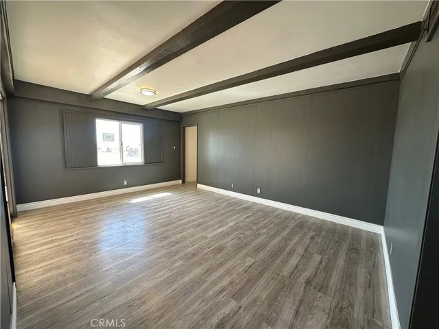 a view of empty room with window and wooden floor