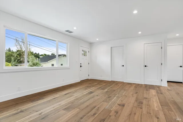 a view of an empty room with wooden floor and a window