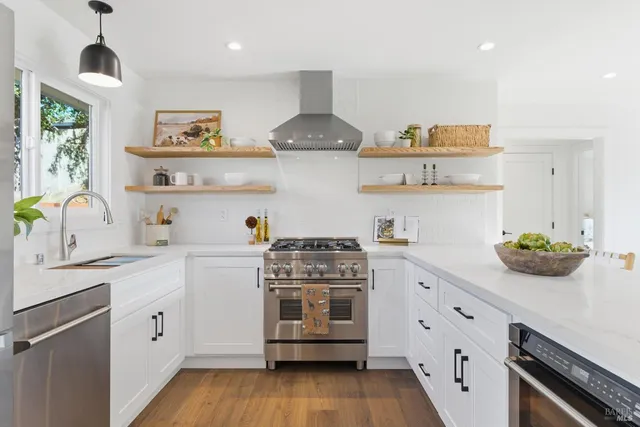 a kitchen with stainless steel appliances a stove and white cabinets
