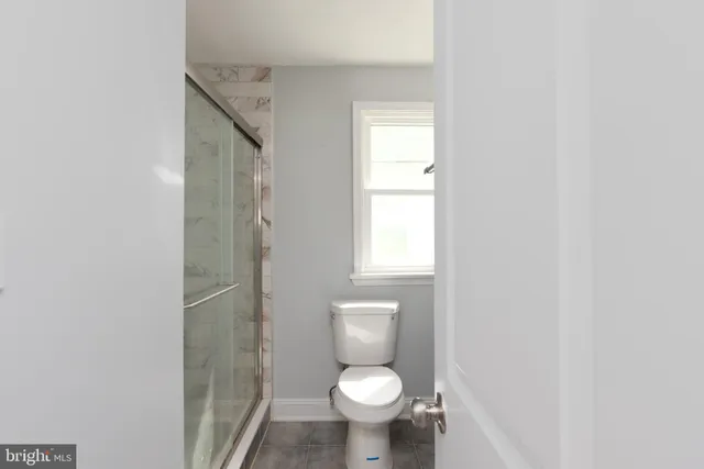 a white toilet sitting in a bathroom next to a window