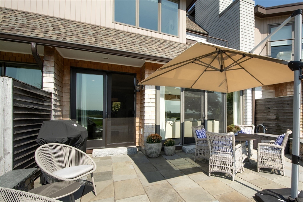 16 Ladds Way, Unit 16 Scituate, MA 02066 - Photo 33 of 40 a view of a patio with a dining table and chairs under an umbrella
