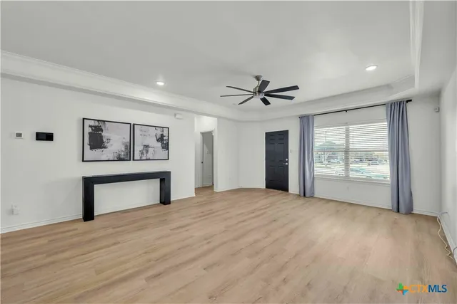 a view of an empty room with a window and wooden floor