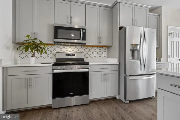a kitchen with stainless steel appliances wooden floor and a refrigerator