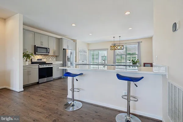a kitchen with stainless steel appliances granite countertop a sink a stove a refrigerator cabinets and a window