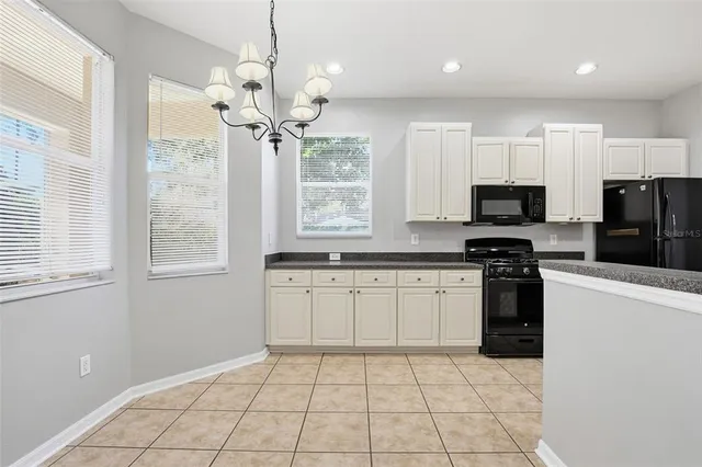 a kitchen with stainless steel appliances granite countertop a refrigerator a sink a stove top oven and a window