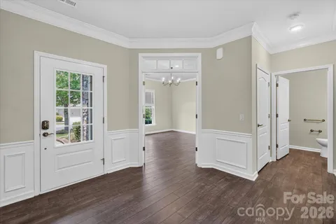 a view of an empty room with wooden floor chandelier and a window