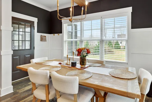 a dining room with wooden floor a chandelier a wooden table and chairs