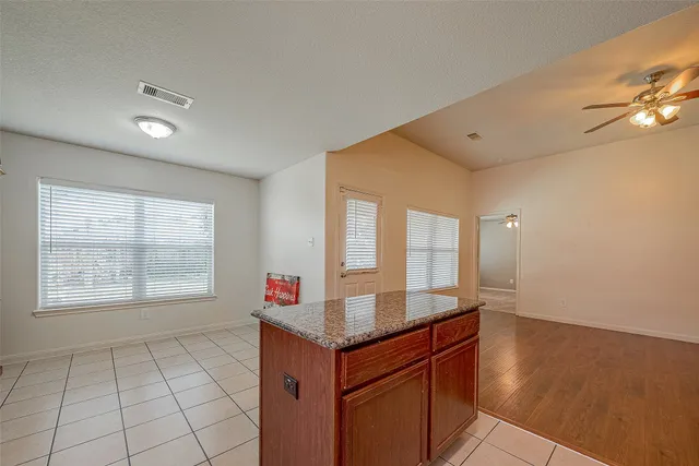 a hall with kitchen island granite countertop white cabinets and window