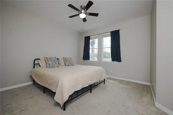 a spacious bedroom with a bed and a ceiling fan