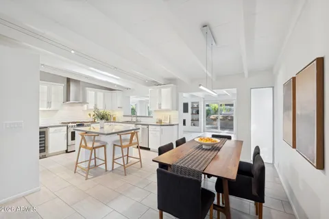 a open dining room with stainless steel appliances kitchen island granite countertop a dining table chairs and a refrigerator