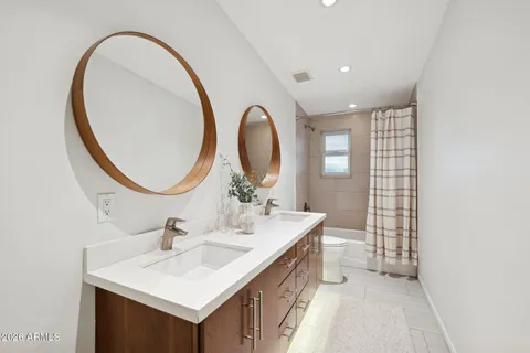 a bathroom with a sink a toilet a mirror a vanity a bathtub and shower