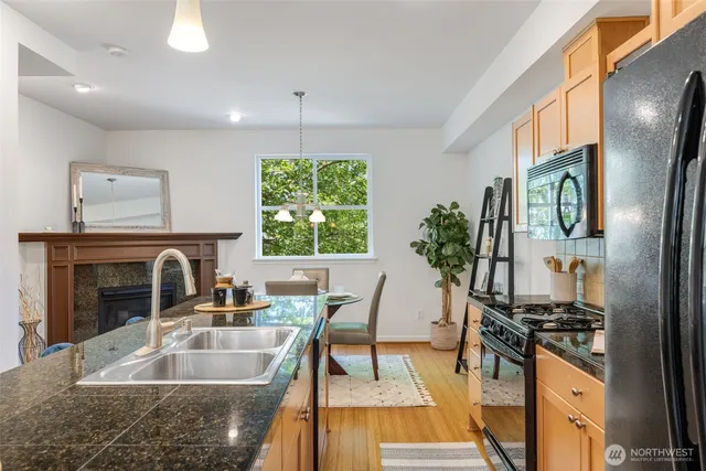 a kitchen with granite countertop a stove a sink a dining table and chairs with wooden floor