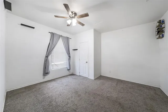 an empty room with a ceiling fan and window