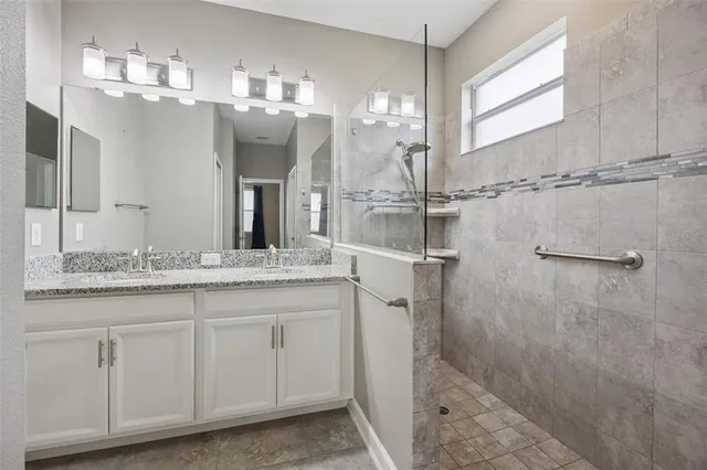a bathroom with a granite countertop sink a mirror and shower