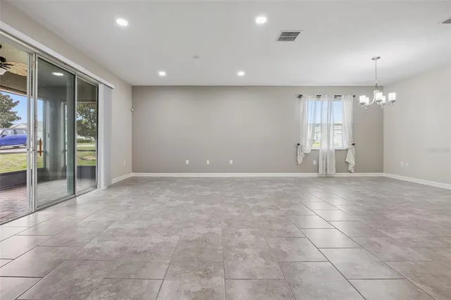 a view of an empty room with glass door and chandelier