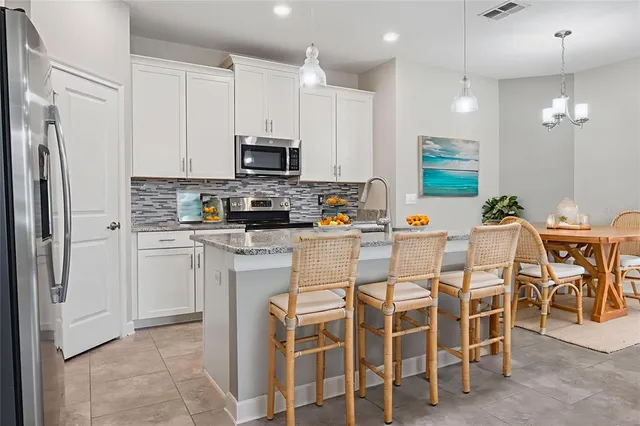 a kitchen with stainless steel appliances kitchen island granite countertop a table chairs microwave and sink