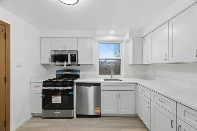a kitchen with a sink cabinets stainless steel appliances and a window