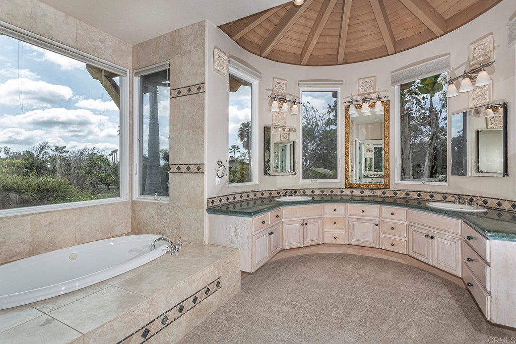 6944 Rancho Cielo Rancho Santa Fe, CA 92067 - Photo 17 of 37 a bathroom with a tub a double vanity sink and a large mirror