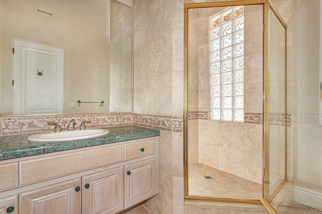 6944 Rancho Cielo Rancho Santa Fe, CA 92067 - Photo 20 of 37 a bathroom with a granite countertop sink a mirror and a shower