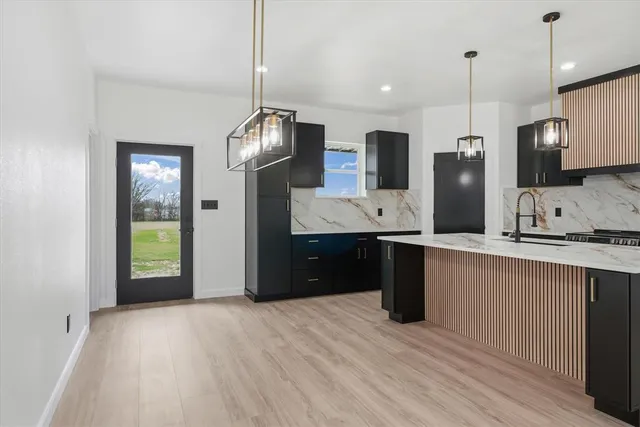 a kitchen with stainless steel appliances granite countertop a refrigerator a sink dishwasher and a wooden floor
