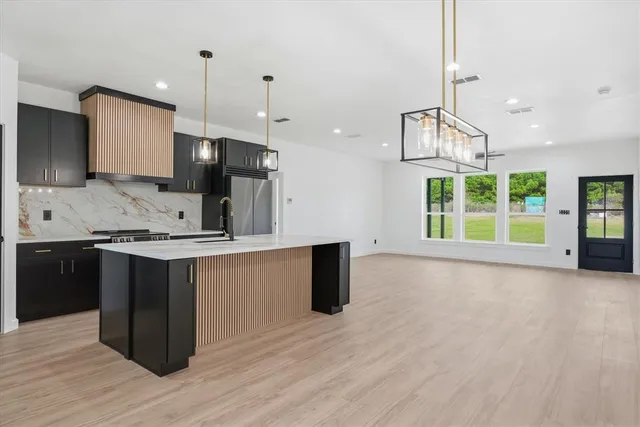 a large kitchen with kitchen island a large counter top space a sink stainless steel appliances and cabinets