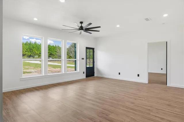 a view of empty room with wooden floor and fan
