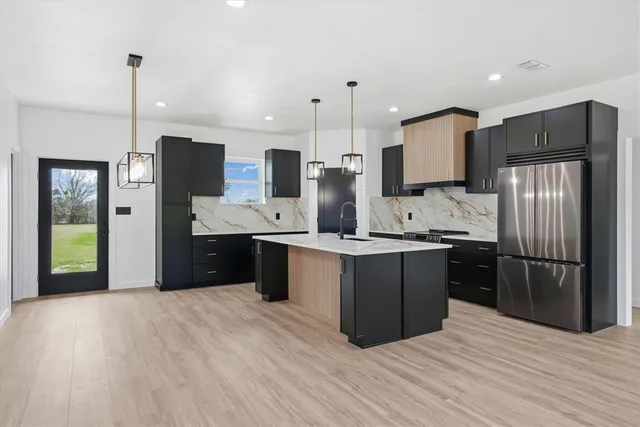 a kitchen with stainless steel appliances kitchen island granite countertop a refrigerator a sink a stove and oven