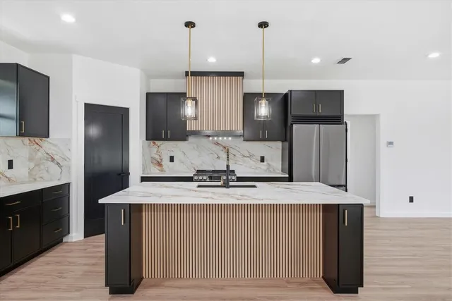 a kitchen with stainless steel appliances granite countertop a sink a refrigerator and a stove