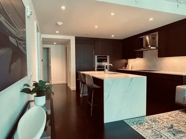 a kitchen with stainless steel appliances kitchen island granite countertop a sink a stove a microwave a refrigerator and cabinets