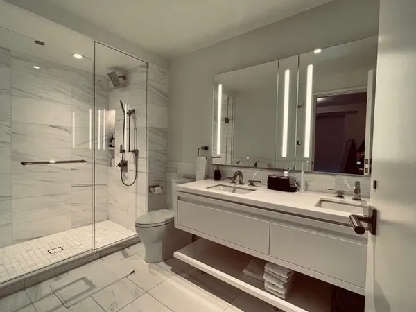 a bathroom with a double vanity sink toilet mirror and shower