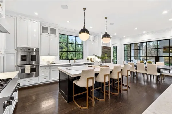 a dining hall with stainless steel appliances kitchen island granite countertop a stove a sink a dining table and chairs with wooden floor