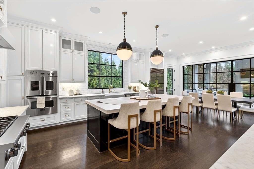 a dining hall with stainless steel appliances kitchen island granite countertop a stove a sink a dining table and chairs with wooden floor