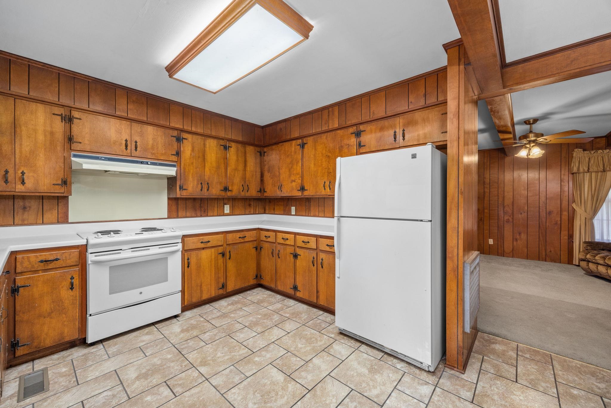 213 Forrest School Road Corinth, MS 38834 - Photo 12 of 40 Kitchen featuring ceiling fan, light colored carpet, white appliances, and wooden walls