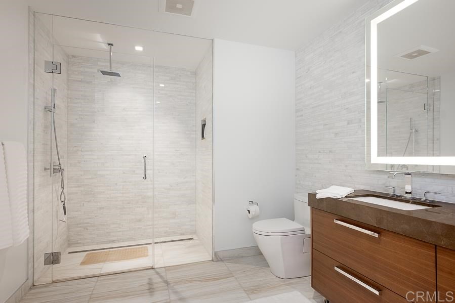 888 West E Street San Diego, CA 92101 - Photo 23 of 30 a bathroom with a granite countertop sink a toilet and shower