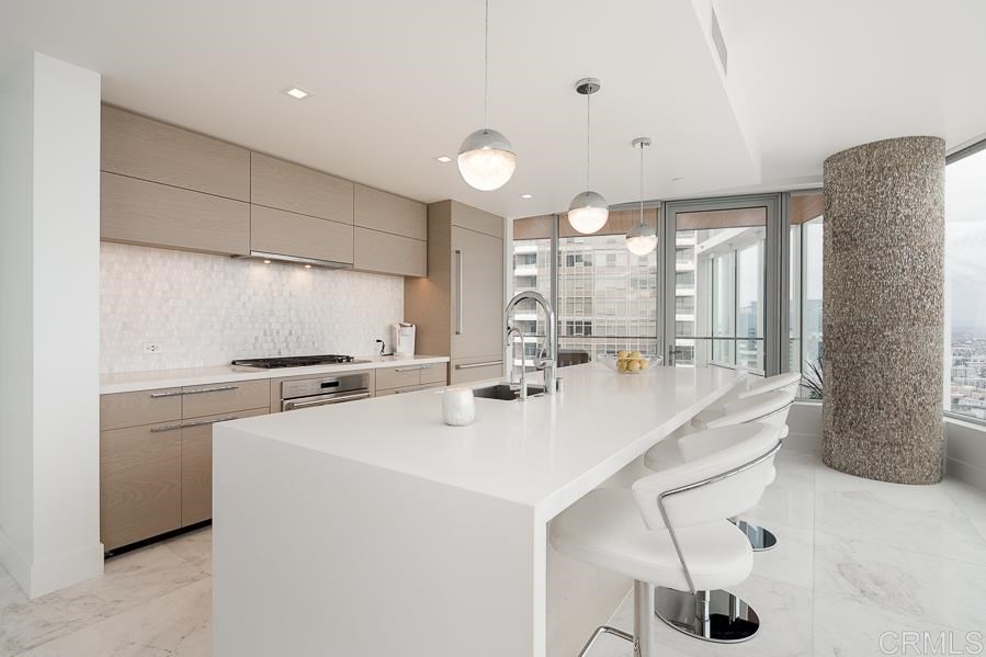 888 West E Street San Diego, CA 92101 - Photo 4 of 30 a kitchen with stainless steel appliances a table chairs and a refrigerator