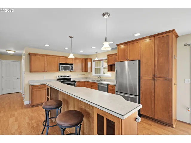 a kitchen with stainless steel appliances granite countertop a table chairs and a refrigerator
