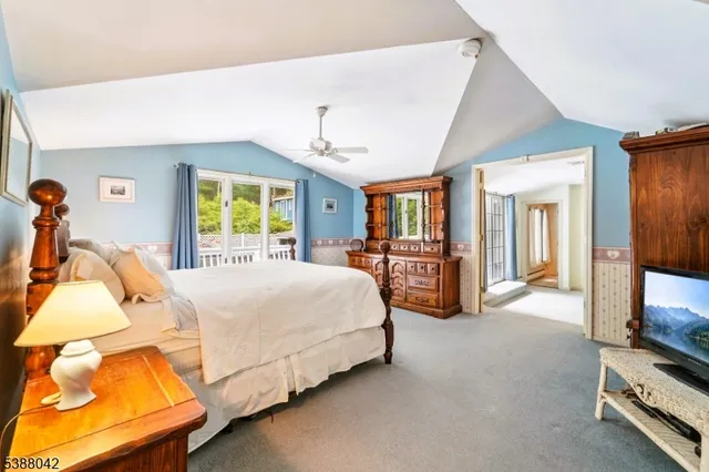 a spacious bedroom with a bed a mirror on dresser and a chandelier
