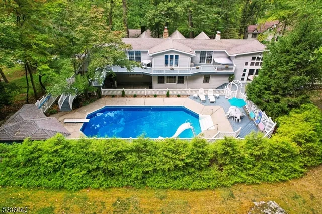 a aerial view of a house with swimming pool lawn chairs and a yard