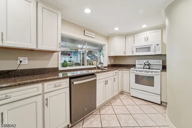 a kitchen with granite countertop white cabinets and white appliances