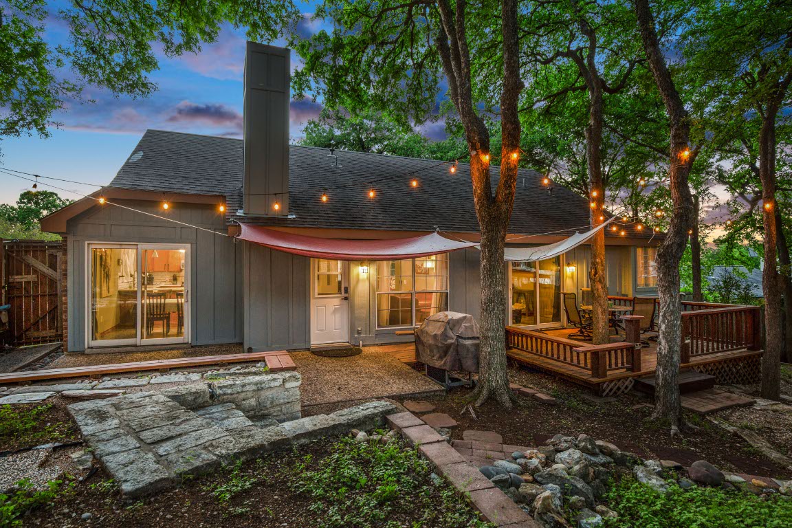 3015 Sunridge Drive Austin, TX 78741 - Photo 1 of 35 Back of house at dusk featuring board and batten
siding, fence, a shingled roof, and a deck