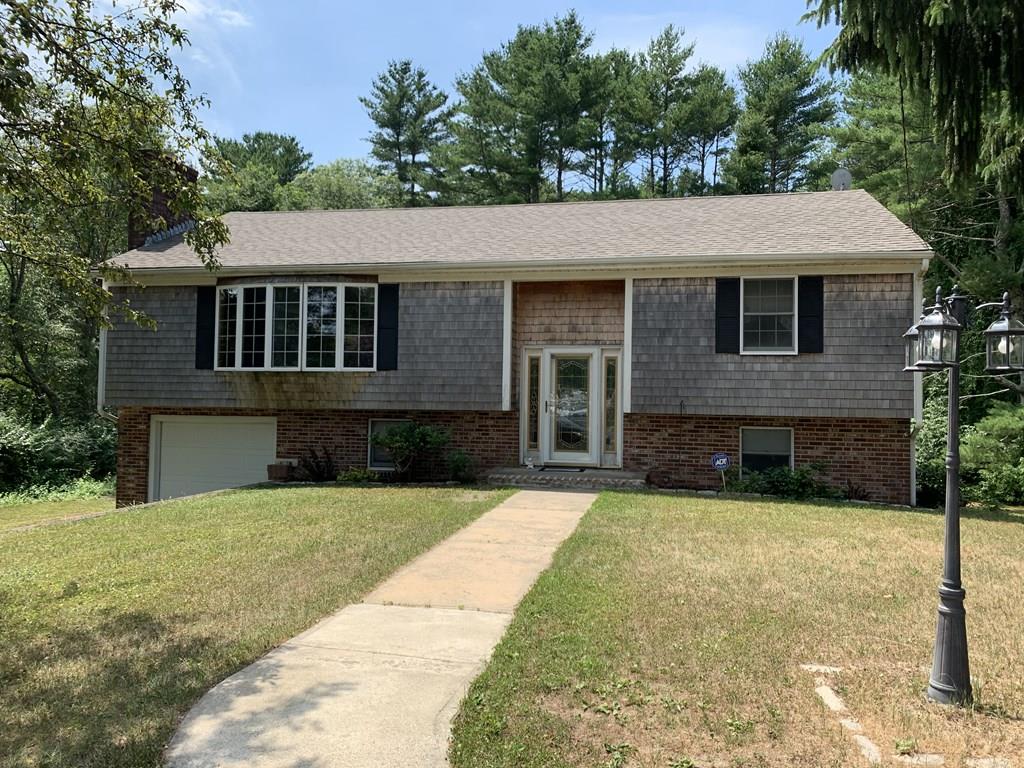 a view of a house with a yard plants and large tree
