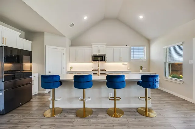 a kitchen with stainless steel appliances kitchen island granite countertop a refrigerator and a stove top oven